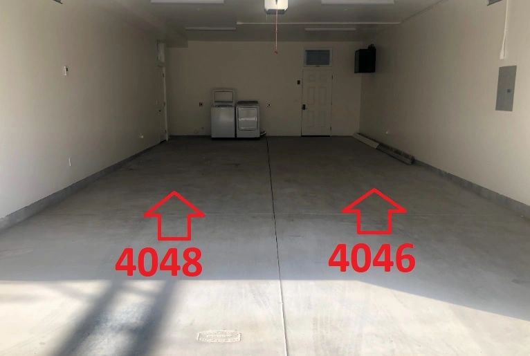 Empty garage with two red arrows and numbers 4048 and 4046 on the floor.