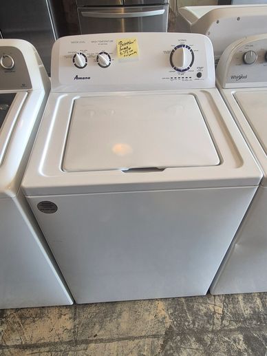 White Amana top-load washing machine with control dials and a sticky note.