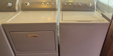 A beige washing machine and dryer set side by side in a laundry room.