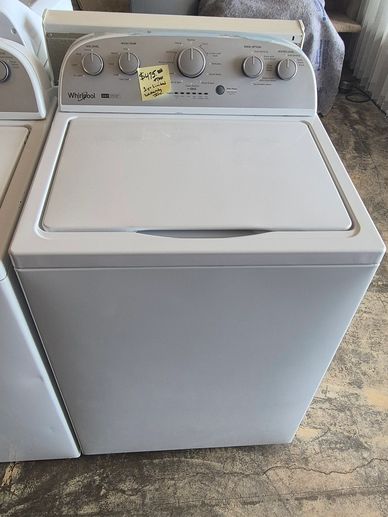 White Whirlpool washing machine with control knobs and a price tag on top.