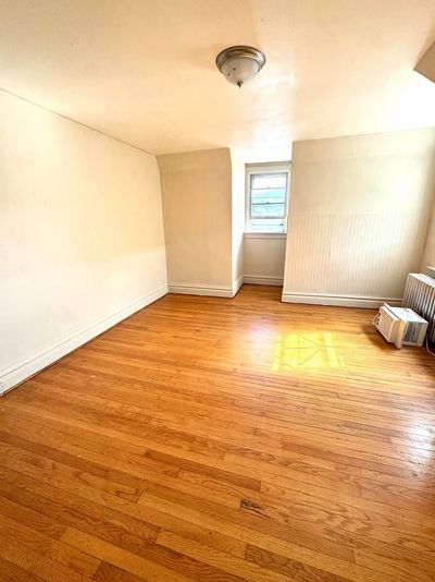 Empty room with hardwood floors and a small window.