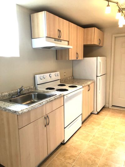 Compact kitchen with light wood cabinets and white appliances.