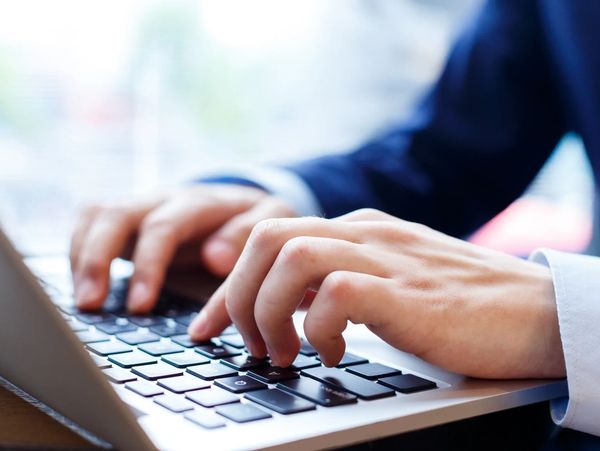 Hands typing on a laptop keyboard.