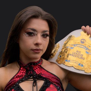 A female wrestler holding a Big League Wrestling championship belt.