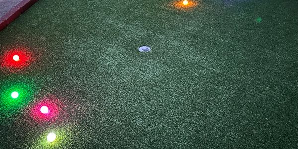Mini golf course hole with colorful LED lights around the edge.