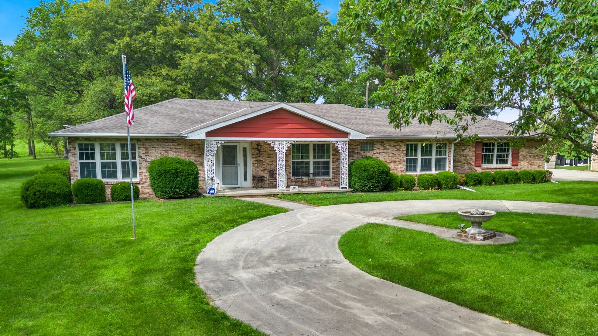 Single-story brick house with circular driveway and lush green lawn.