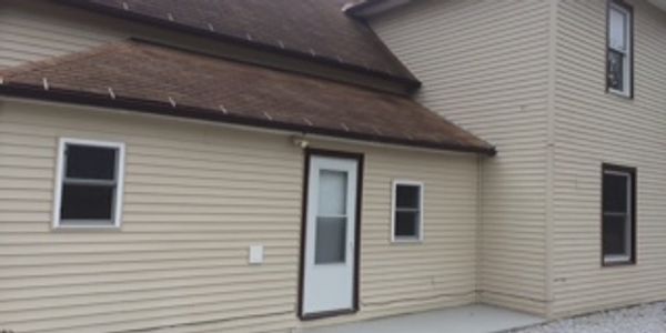 Exterior view of a beige house with white door and windows.