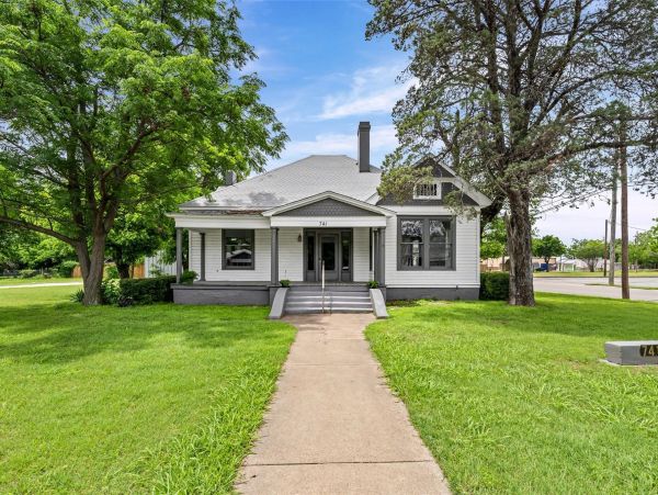 Classic white house with green lawn and two large trees.