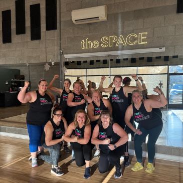 Group of women flexing muscles in a fitness studio.