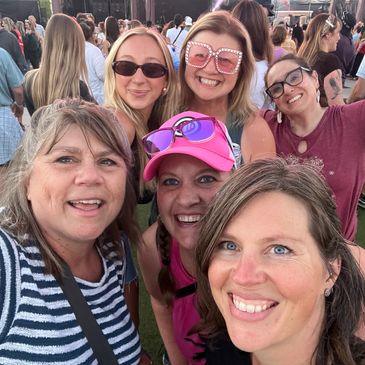 Group of six women smiling at an outdoor event.