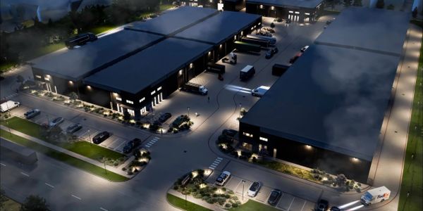 Night view of an industrial complex with multiple warehouses and parked vehicles.