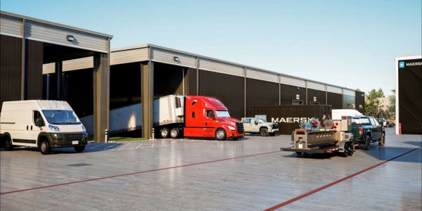 Trucks and vans parked outside a distribution warehouse.