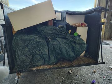 A dumpster filled with various discarded household items and boxes.