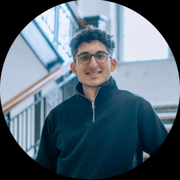 Young man smiling indoors near a staircase.