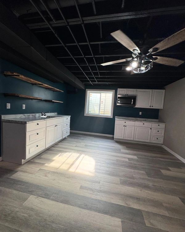 Modern kitchen with white cabinets and dark ceiling fan.