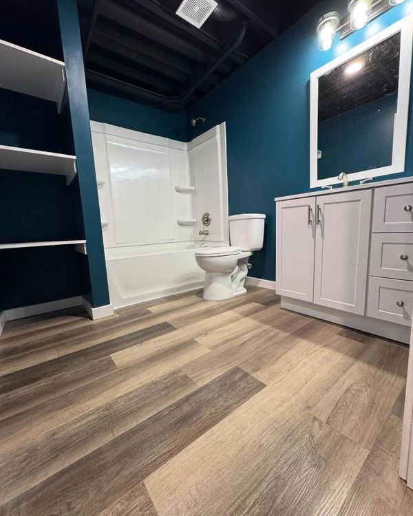 Modern bathroom with wood-style flooring and blue walls.