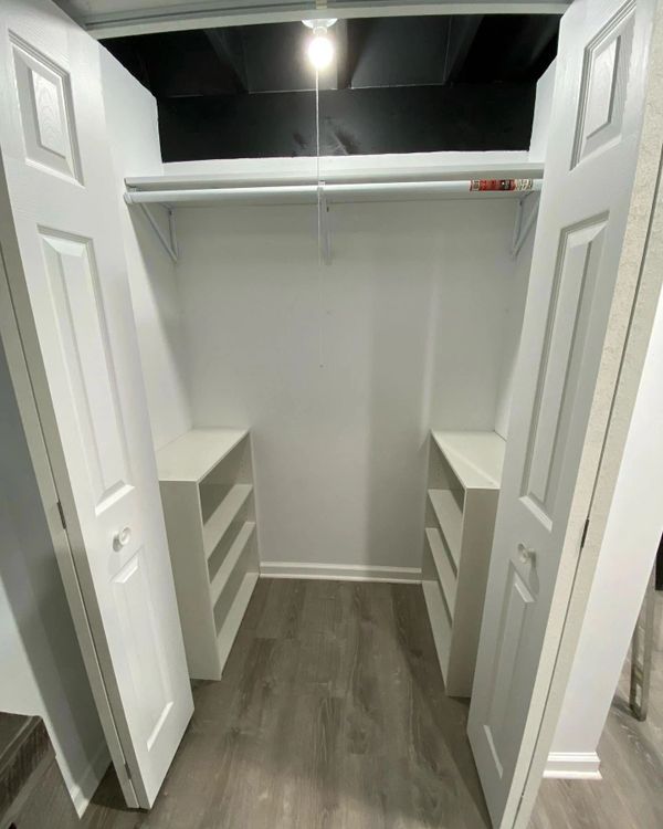Empty walk-in closet with white shelves and hanging rod.