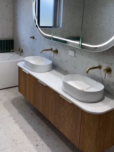 Modern bathroom with dual vessel sinks and illuminated mirror.
