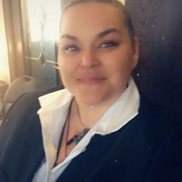 Smiling woman dressed in formal attire, posing indoors.