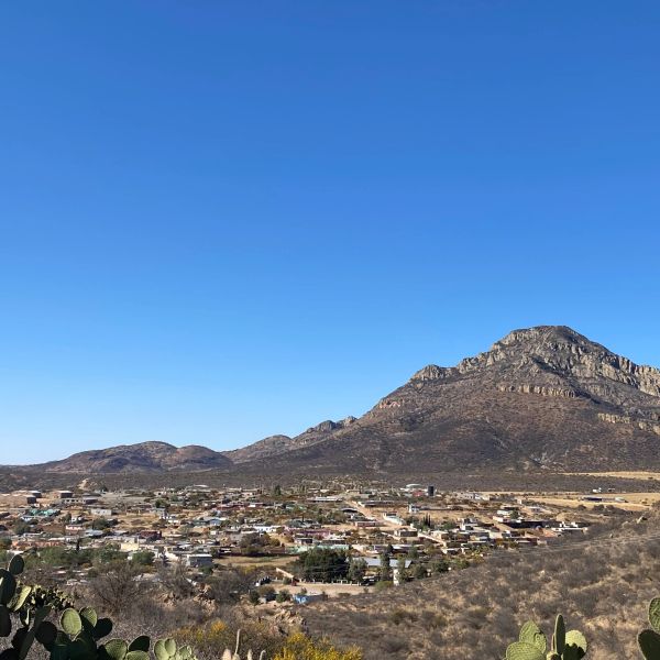 Small town nestled at the base of a rugged mountain under a clear blue sky.
