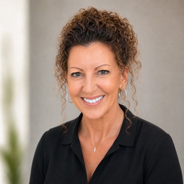 Smiling woman with curly hair in a black shirt.