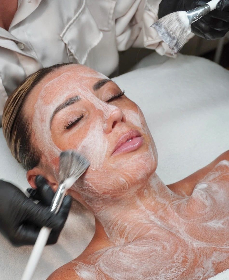 Woman receiving facial treatment with brushes.