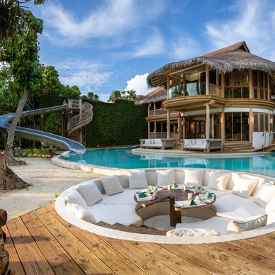 Luxurious tropical villa with pool, slide, and sunken seating area for dining.