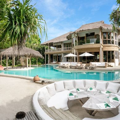 Luxurious tropical villa with pool, outdoor dining, and lush greenery.