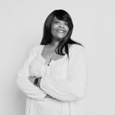 Black & White photo of smiling woman with arms crossed.