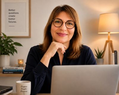 Smiling woman with glasses working on a laptop.