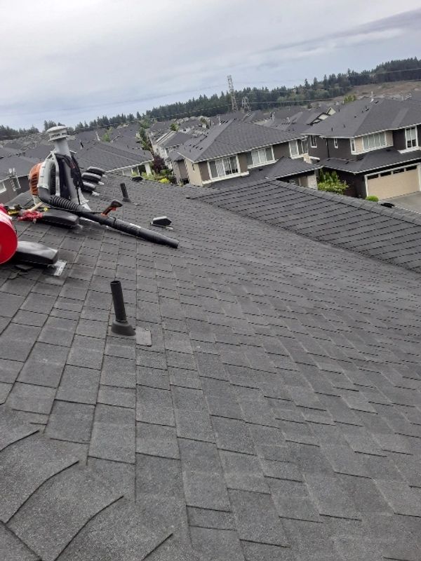 View of a residential neighborhood roof with roofing tools placed on it.