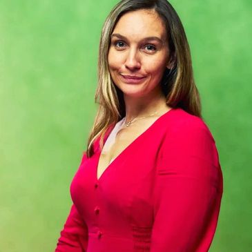 Woman in a red dress posing against a green background.