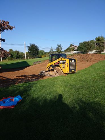 Wally, the skid loader, stripped the topsoil to prepare for the excavated dirt from a foundation.