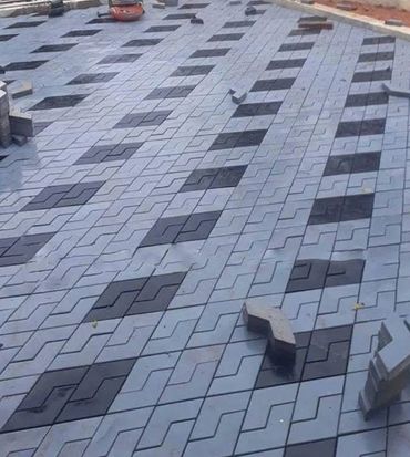 Patterned interlocking pavement tiles being installed outdoors.