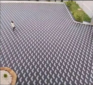 Person walking on a patterned pavement with 3D optical illusion blocks.