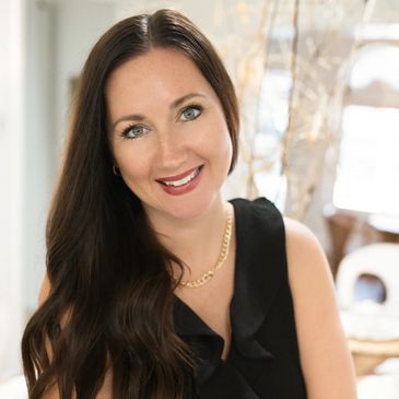 Smiling woman with long brown hair in a black sleeveless top.