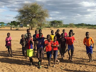Refugee Children Walking Through A Dirt Field After Playing Soccer