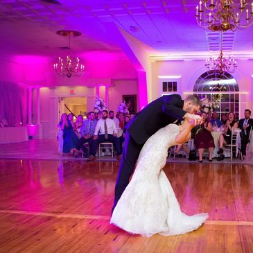 Photo of groom kissing bride during their wedding first dance with brilliant purple uplighting.