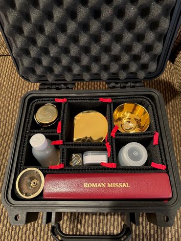 A religious kit with a Roman Missal and golden items in a padded case.