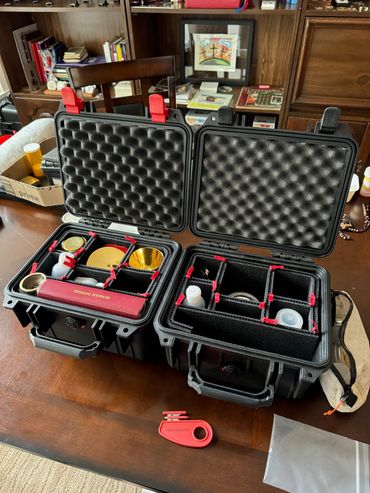 Two open black protective cases with compartments on a wooden table.
