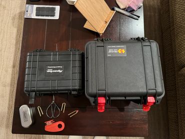 Two black rugged cases and fishing accessories arranged on a table.