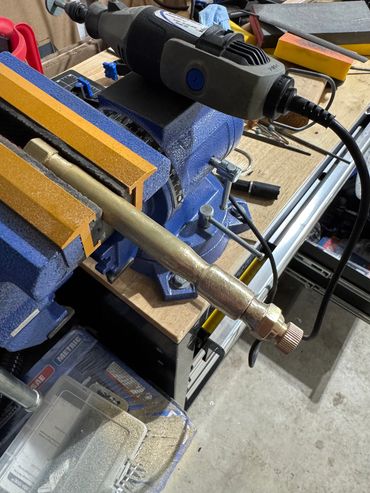 Metal pipe held in a blue and orange vise.