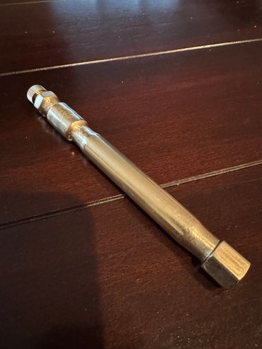 A metallic valve extension on a wooden surface.