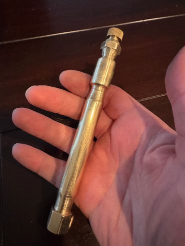 Hand holding a metallic tool or component.