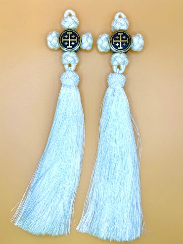 Two white knotted crosses with long tassels on tan background.