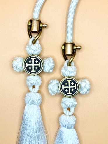Decorative white tassels with gold and black cross emblems.