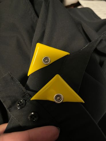 Yellow triangular clips on a black fabric.