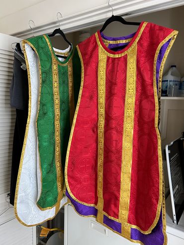 Two ornate religious vestments hanging on hangers.