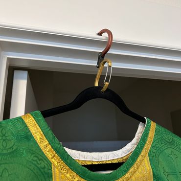 Green and gold dress hanging on a black hanger.