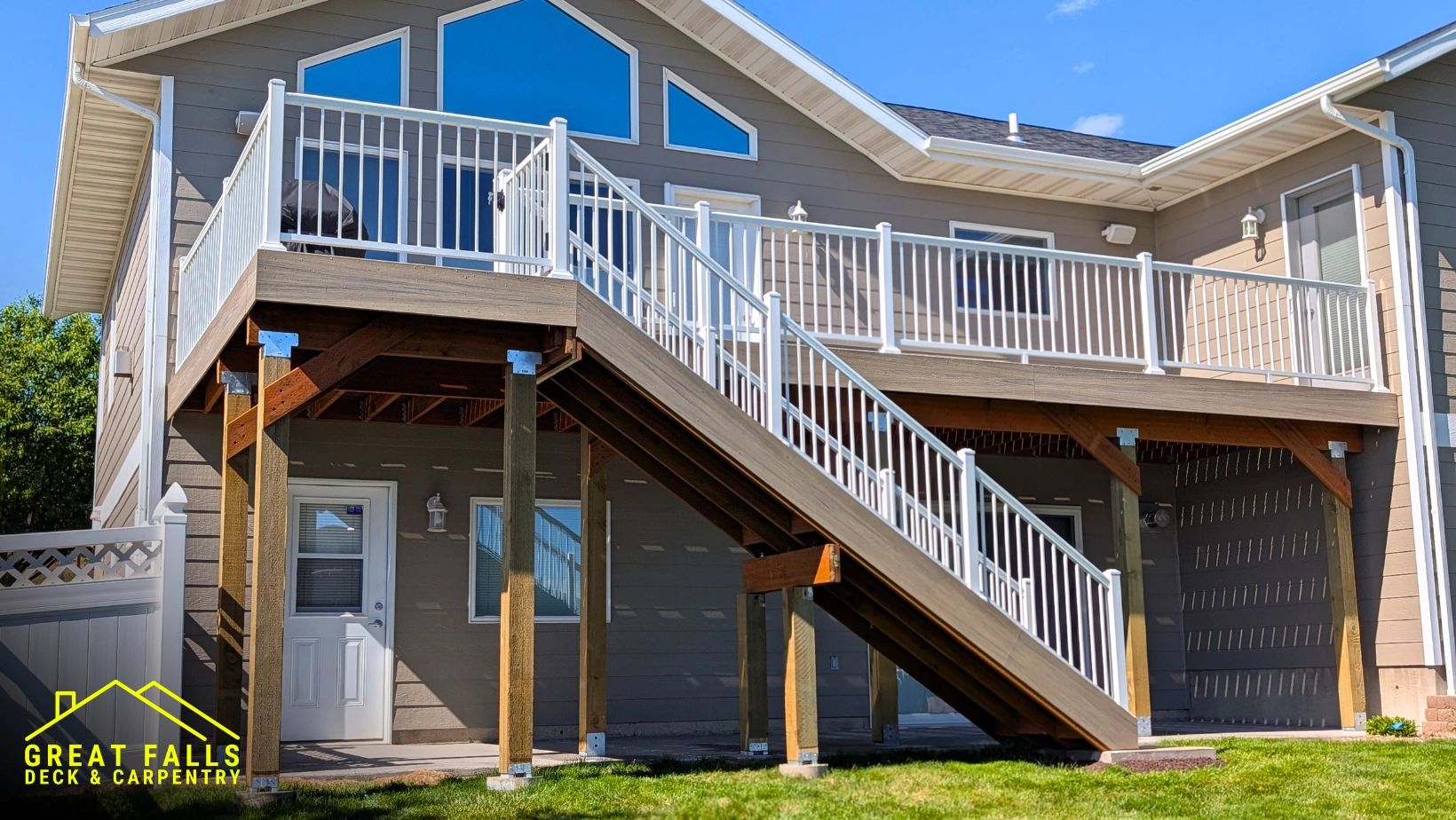 Elevated wooden deck with white railing and stairs on a residential house.